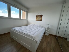 A bedroom with a bed, a nightstand, a hanging map, and a wardrobe.