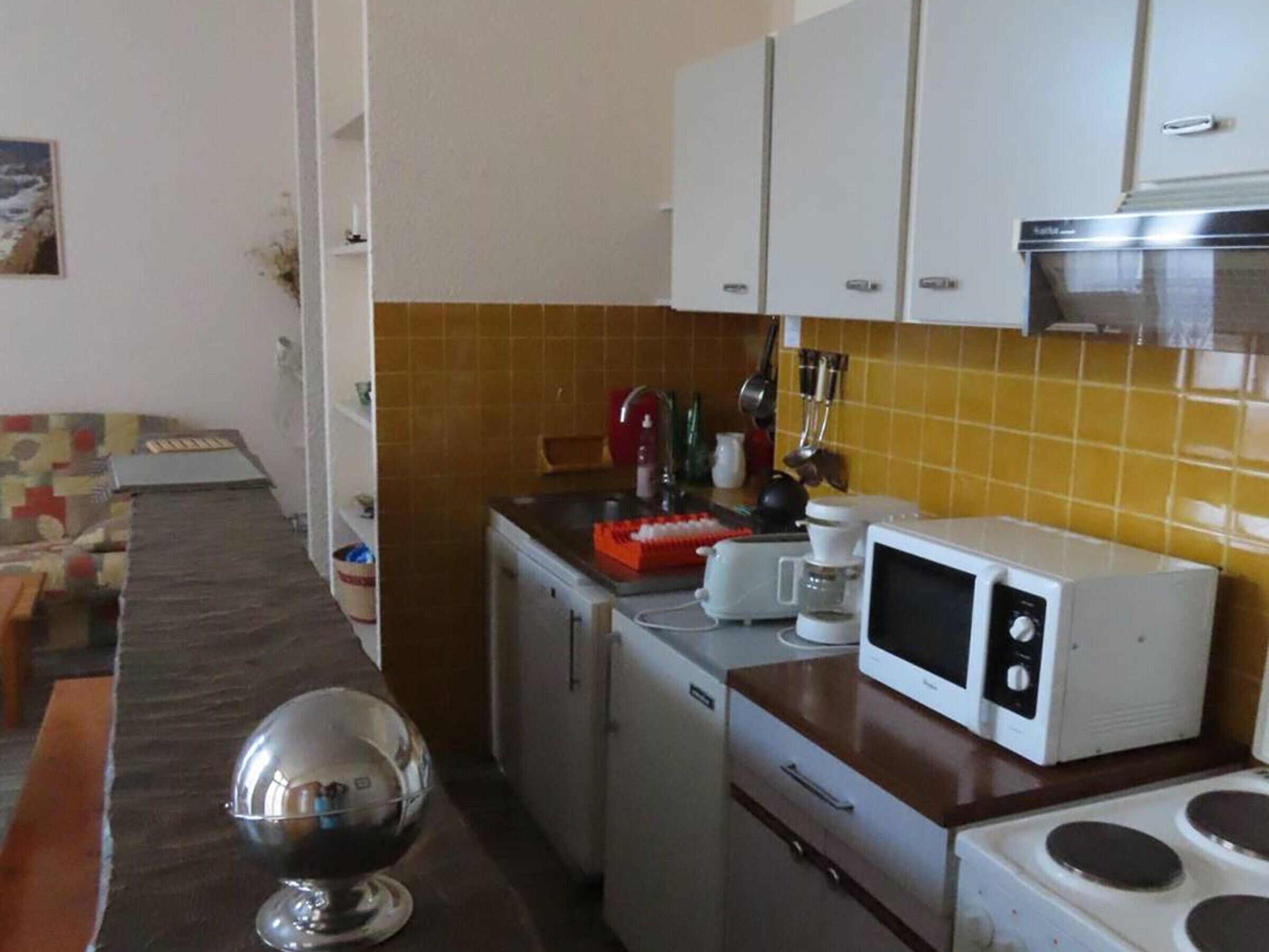 A compact kitchen with white cabinets, a microwave, a stove, and a small refrigerator.