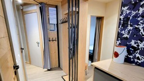A hotel room with a wooden floor, a bed with a blue headboard, a small table with a white mug, and a wall with a blue and white abstract pattern. - Renovated apartment, ski-in/ski-out, balconies, 3 rooms for 8 ppl. (Les Arcs 2000)