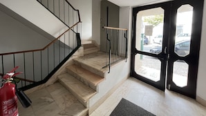 A staircase with a black railing and a fire extinguisher on the floor. - A Casa de Sesimbra com VISTA MAR (Sesimbra)