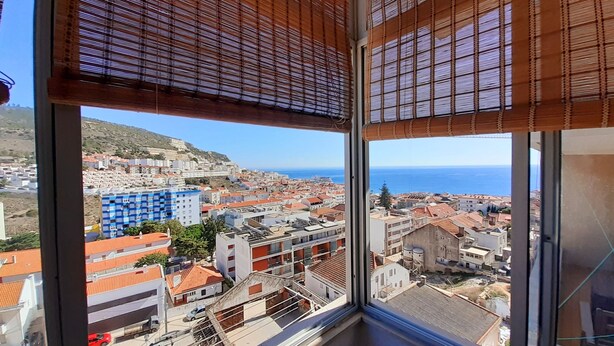 A high-rise building with large windows overlooking a coastal cityscape. - A Casa de Sesimbra com VISTA MAR (Sesimbra)