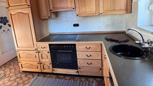 Eine kleine Küche mit Holdekor-Schränken, einem Backofen und einem Spülbecken.
