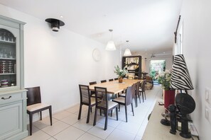 A dining area with a wooden table and chairs, a cabinet with glass doors, pendant lights, and a zebra-striped lamp.
