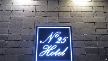 A neon sign on a brick wall that reads "No 25 Hotel".