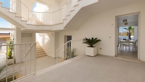 Un intérieur spacieux avec un escalier central, un coin repas et une grande plante en pot.