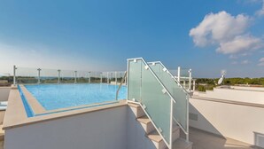 Une piscine sur le toit, dotée de rampes en verre et offrant une vue dégagée sur le paysage environnant.