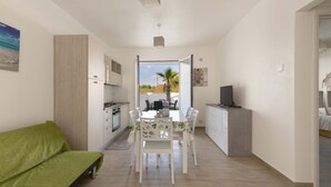 Une cuisine moderne avec des meubles blancs, une table à manger avec des chaises et une vue sur l’extérieur.