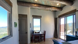 A room with a dining area, a bed, and large windows with a view.
