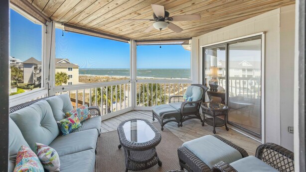 A covered outdoor balcony with a ceiling fan, wicker furniture, and a view of the beach. - Oceanfront Condo in WILD DUNES! Fully Renovated with Rooftop Balcony! (Isle Of Palms)