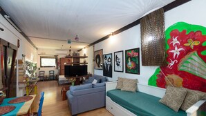 A cozy living room with a sofa, a TV, and a dining area with a table and chairs.