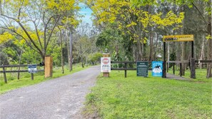 Enter a serene horse riding facility with a gravel path leading to a welcoming center.