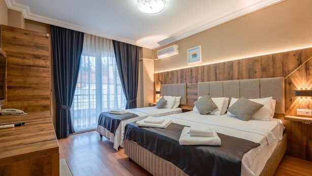 Une chambre d’hôtel avec deux lits, un bureau en bois et une grande fenêtre avec des rideaux.