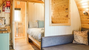 Ein Holzblockhaus-Interieur mit Bett, Sofa, Decke und Feuerlöscher.