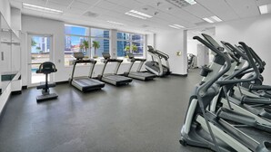 Uma academia com esteiras, elípticos e um banco de musculação.