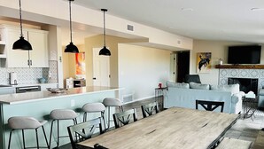 A modern kitchen with a central island, bar stools, and pendant lighting.