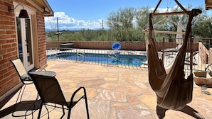 A patio with a pool, outdoor furniture, and a hanging chair.