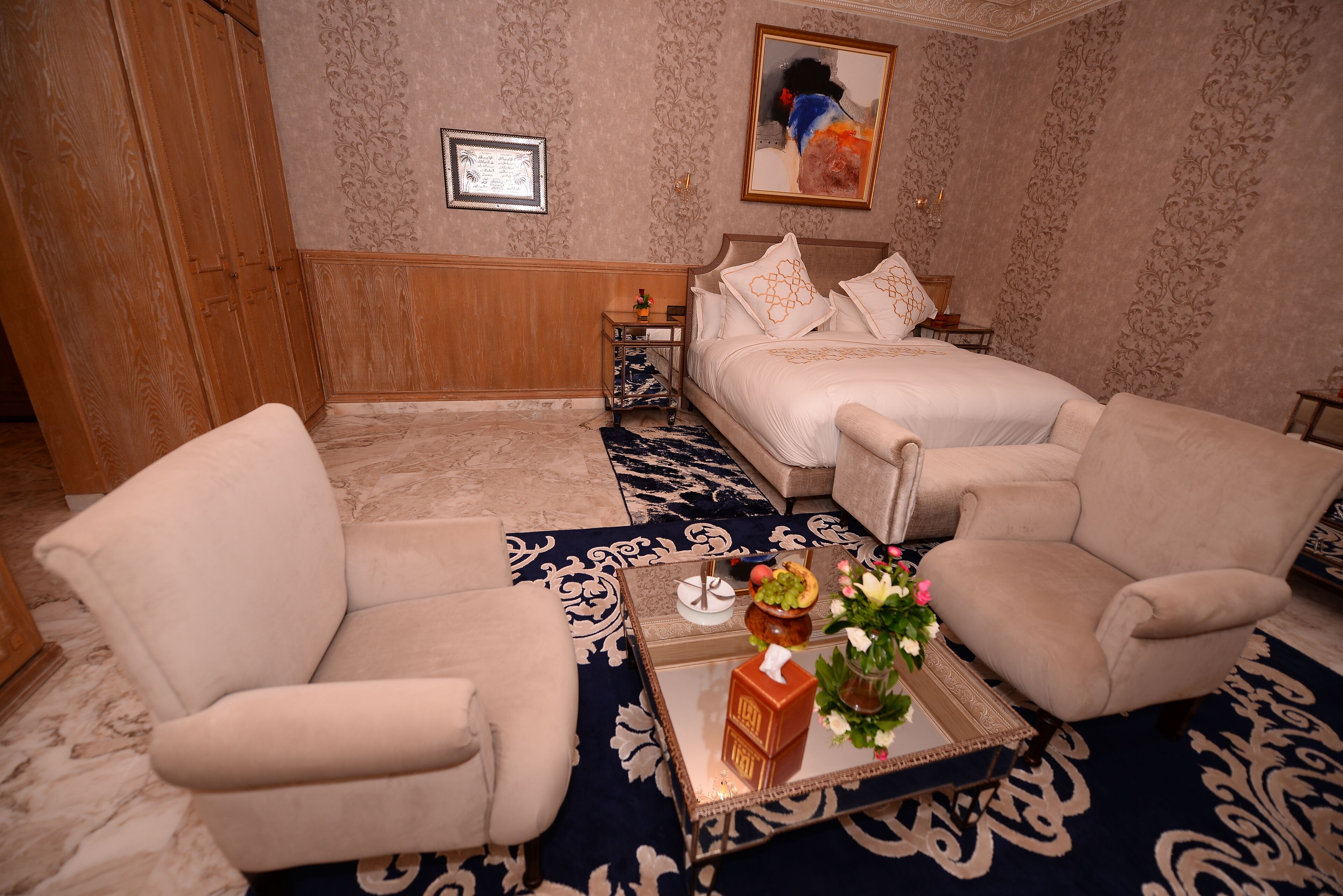 Ein Hotelzimmer mit einem Bett, zwei Sesseln, einem Couchtisch mit Tablett und einem Gemälde an der Wand.