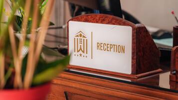 A reception desk with a sign reading "RECEPTION" and a potted plant in the foreground.