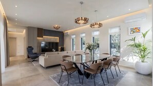 Una sala de estar moderna con televisor grande, sofá y comedor.
