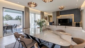 Un comedor moderno con una gran mesa ovalada, varias sillas y un jarrón de flores.