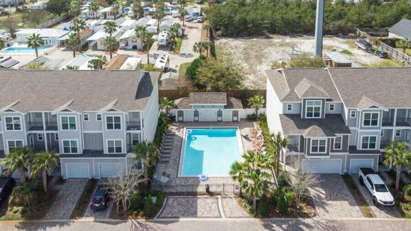 Un quartier résidentiel avec des maisons à deux étages, une piscine et des voitures garées.