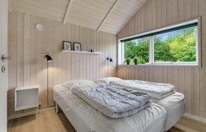 Relax in a serene bedroom with a comfortable bed, bedside table, and wall-mounted shelf displaying personal touches.