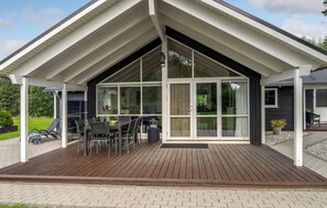 Enjoy meals on the spacious patio with a dining table and chairs, surrounded by a glass door offering a view into the interior.