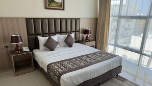 A modern hotel room with a large bed, two bedside tables, a headboard, and a view through a large window. - PRIMOTEL Suites Al Salamah (Jeddah)