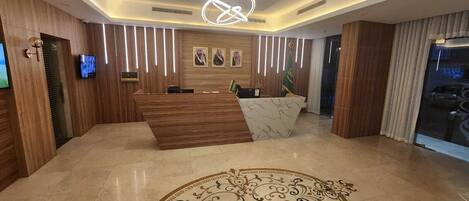 A reception area with a wooden reception desk, a marble counter, and a patterned carpet.