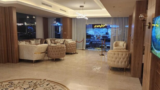 A spacious lobby with a large, plush sofa set, a television mounted on the wall, and a decorative rug. - PRIMOTEL Suites Al Salamah (Jeddah)