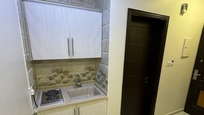 A compact kitchen with a sink, cabinets, and a stove. - PRIMOTEL Suites Al Salamah (Jeddah)