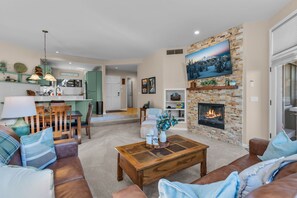 Una sala de estar moderna con chimenea, un comedor y una cocina.