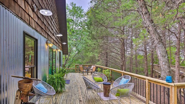Una terraza de madera con mobiliario exterior, una silla de metal y un cubo r ústico.