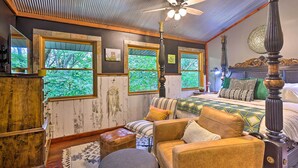 Una habitación acogedora con cama, un armario de madera, un sofá y una ventana con vistas a árboles.
