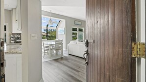 A modern kitchen with white cabinets, a granite countertop, and a dining area with a white table and chairs. - 2 bedroom villa just steps to the pool with a fantastic lagoon view! (Hilton Head Island)