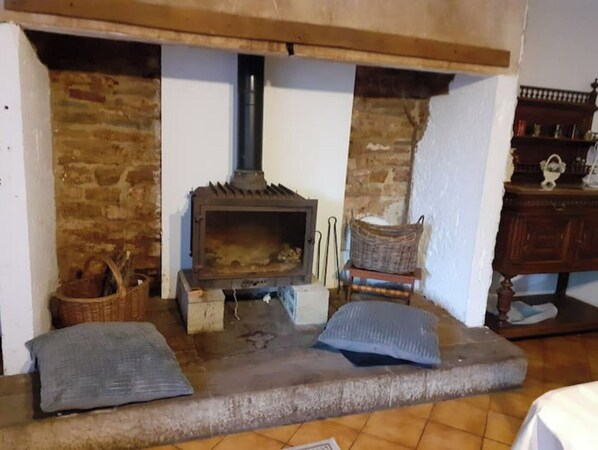 A rustic room with a stone fireplace, a wooden bench, and a small table with a basket.