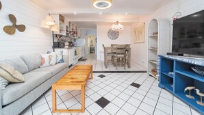 A modern living room with a sofa, wooden coffee table, and a TV stand. - Beachers 421: stunning oceanfront, steps to pool, pet friendly. (St. Augustine)