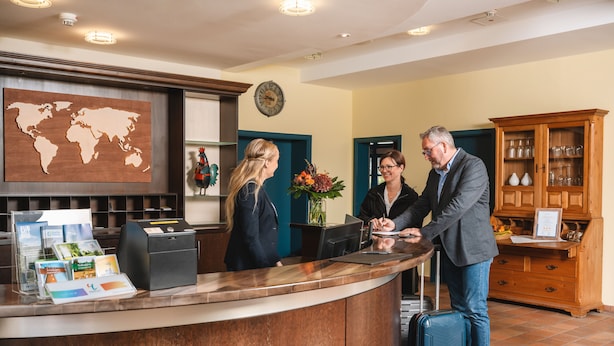 A reception desk with a world map, a clock, and a wooden cabinet with glassware. - Hotel am Park (Hueckelhoven)