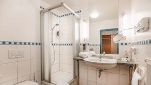 A bathroom with a shower, toilet, sink, and a mirror. - Hotel am Park (Hueckelhoven)