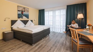 A hotel room with a bed, a desk, a chair, a lamp, and a painting on the wall. - Hotel am Park (Hueckelhoven)