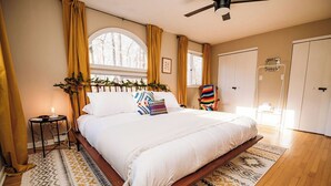 Une chambre à coucher avec un grand lit, une table de chevet, une chaise, une fenêtre et une porte.