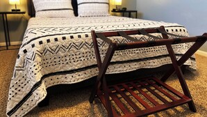 Un lit bien fait, avec une couvre-lit à motifs et des oreillers, une chaise en bois et deux lampes de chevet.