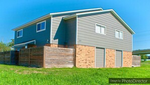 Une maison à deux étages avec un garage, des fondations en briques et un toit en pente.
