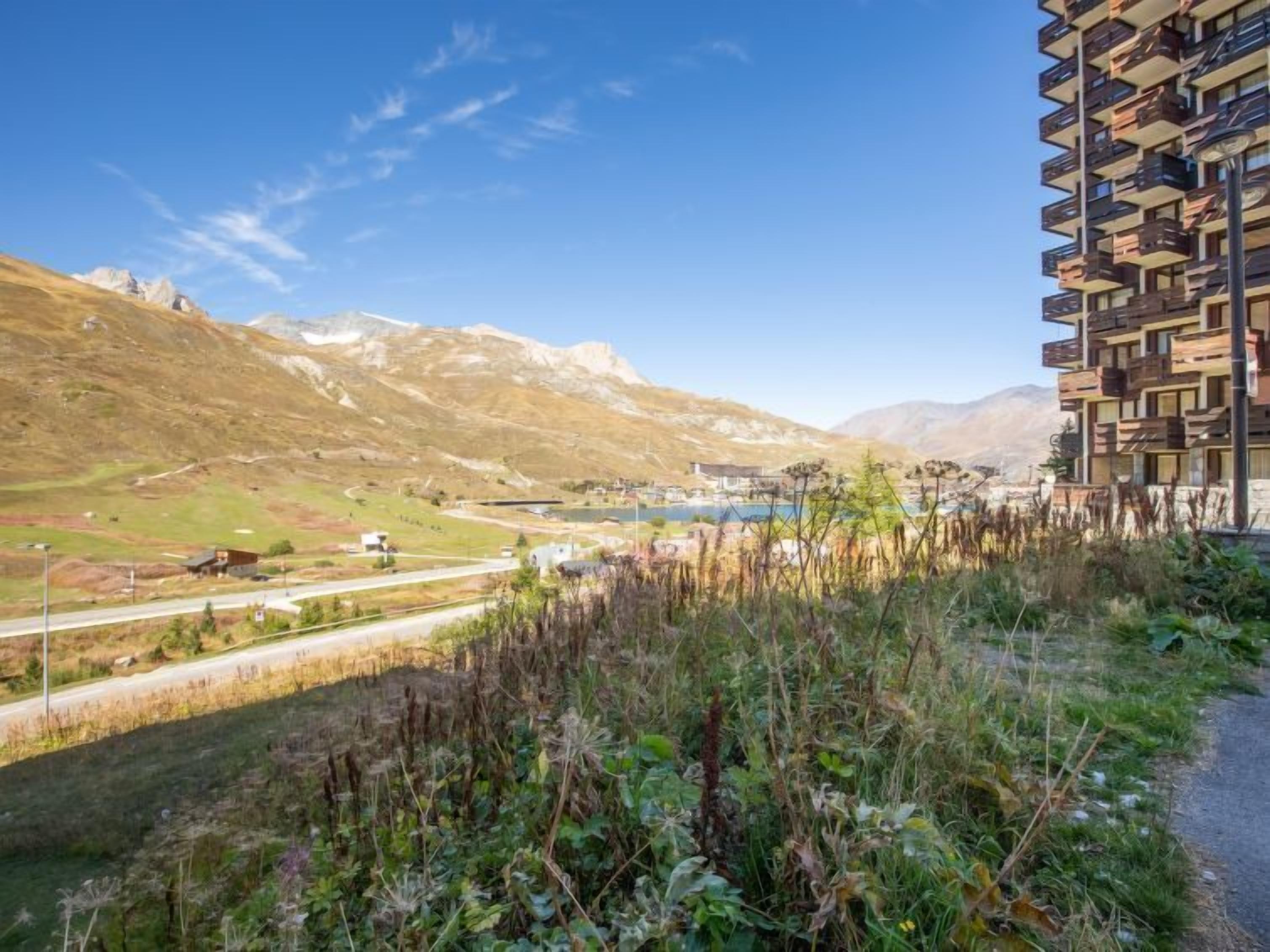 Um edifício moderno com um design arquitetônico único, com várias varandas e vista para uma paisagem montanhosa.