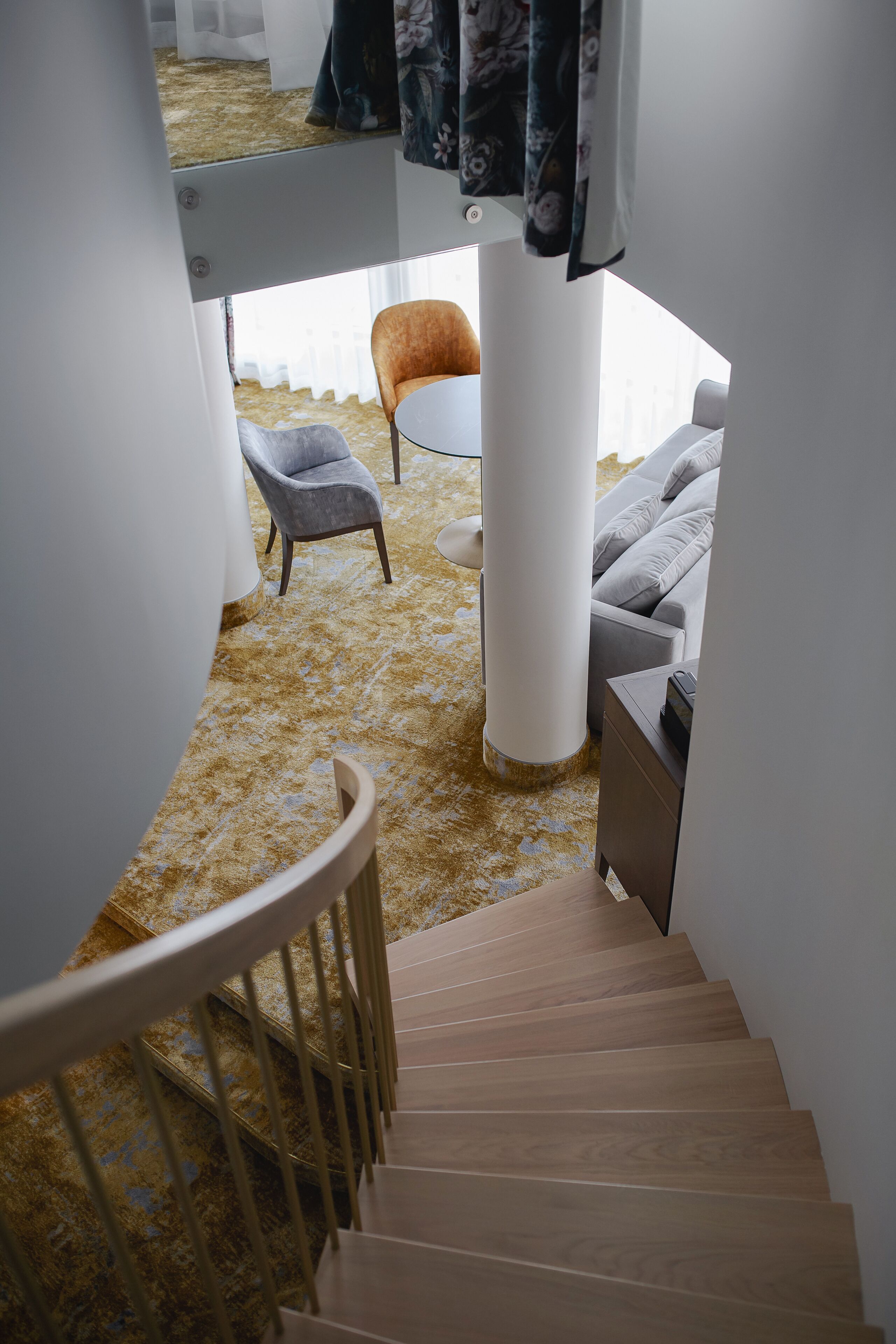 Una escalera conduce a una sala de estar con un sofá, una silla y una mesa de centro.