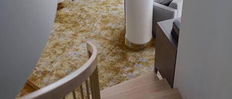 Una escalera conduce a una sala de estar con un sofá, una silla y una mesa de centro.