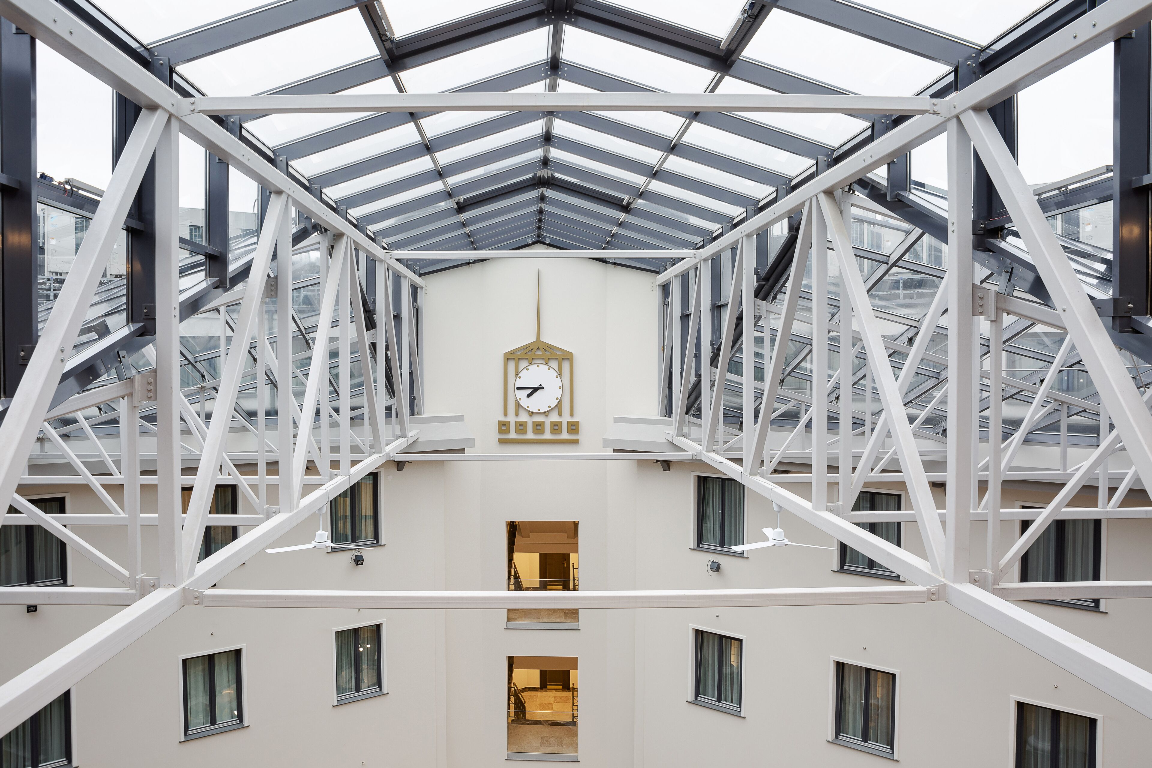 A modern building with a glass roof and a central clock.