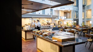 A buffet area with various food options and a seating area with tables and chairs. - VICTORIA Hotel Klaipėda (Klaipeda)
