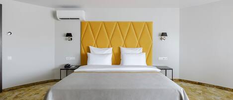 Una habitación de hotel con cama, mesita de noche, lámpara y aire acondicionado.
