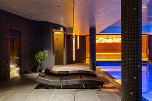 Un vestíbulo moderno con una zona de estar curvada, una piscina e iluminación ambiental cálida.